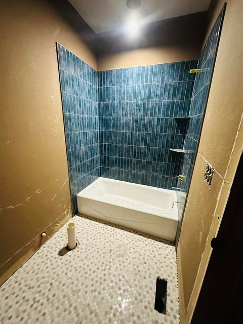 Deep green tub surround with a pebble floor