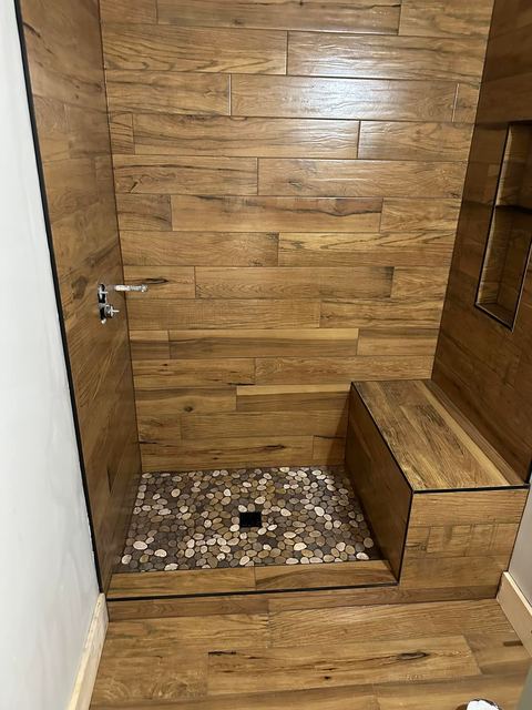 Wood-look plank shower, river rock floor and bench
